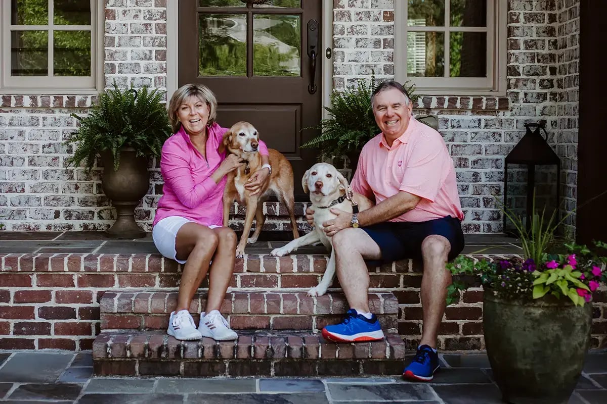 couple with two dogs sitting on brick porch