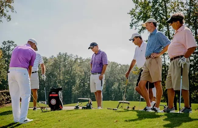 male golfers watching mark blackburn demonstrate